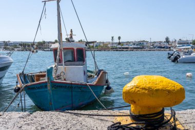 Kos Yunanistan - 25 Ağustos 2024; Mastihari Sahili 'nde büyük sarı kazık ve geleneksel tarz ve mavi-beyaz Yunan balıkçı teknesi.