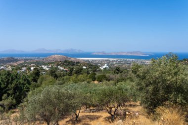 Zeytin bahçesine bakan Kos adasının tepelerinden ve Ege ve diğer Yunan Dodecanese Adaları 'ndaki kiliseli ağaçlardan manzara.