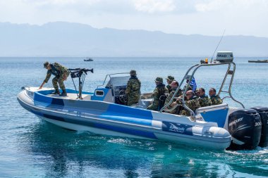 Kalymnos Yunanistan - 27 Ağustos 2024; Bir grup kamuflaj üniformalı adam şişme botla plajdan ayrılıyor.
