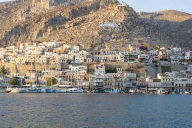 Kalymnos Yunanistan - 28 Ağustos 2024; Rıhtım Kenti Kalymnos Şehri ve yamaçtaki evler demirli teknelerin arkasında.