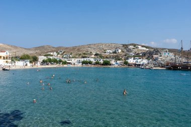 Pserimos Yunanistan - 28 Ağustos 2024; Pserimos Adası 'nın körfezde yüzen turistlerle ve arka planda kalabalık plajlarla dolu bir tatil beldesi.