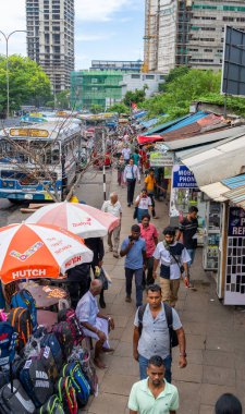 Colombo Sri Lanka - 2 Eylül 2024; Karmaşık çatılar arasında yaya köprüsünün altında ve kentsel gökdelene karşı ayrıntılı olarak dekore edilmiş otobüsler.