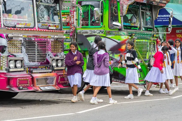 Nuwara Eliya Sri Lanka - 6 Eylül 2024; Beyaz okul üniformalı genç kızlar tipik olarak okuldan sonra Asyalı süslü otobüslerin önünde yürüyorlar.