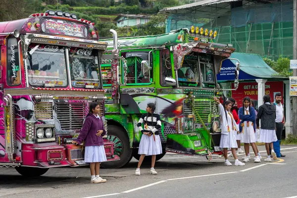 Nuwara Eliya Sri Lanka - 6 Eylül 2024; Beyaz okul üniformalı genç kızlar tipik olarak okuldan sonra Asyalı süslü otobüslerin önünde yürüyorlar.