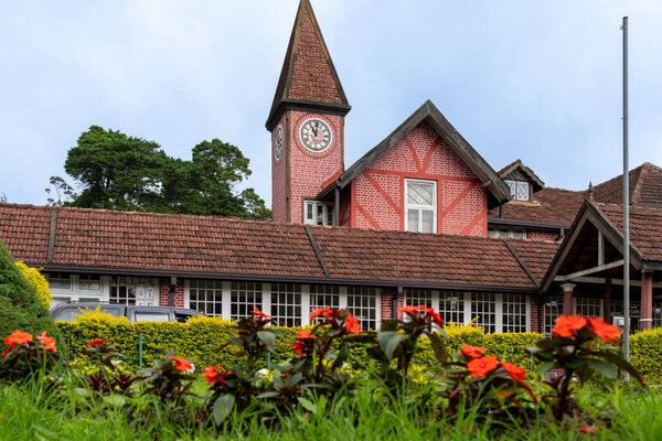 Нувара Элия Шри-Ланка - 6 сентября 2024 года; Интригующе спроектированные часовая башня и циферблат часов на историческом почтовом здании в стиле Тувара с садом на переднем плане.