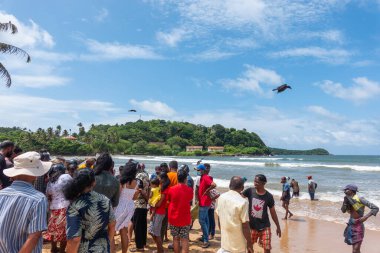 Galle, Sri Lanka - 14 Eylül 2024; Turistler, Sri Lanka 'nın Galle kıyısında balık tutarken yerel köylülerin tezahürat yapmasını izlemek için sahilde toplandılar. Ağ balıkçılığı ya da Ma 'a dal balıkçılığı geleneksel bir yöntemdir.