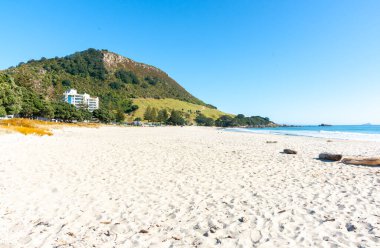 Maunganui Dağı, mavi gökyüzünün altında, uzun kumlu plajın sonunda Yeni Zelanda 'da..