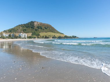 Maunganui Dağı, mavi gökyüzünün altında, uzun kumlu plajın sonunda Yeni Zelanda 'da..