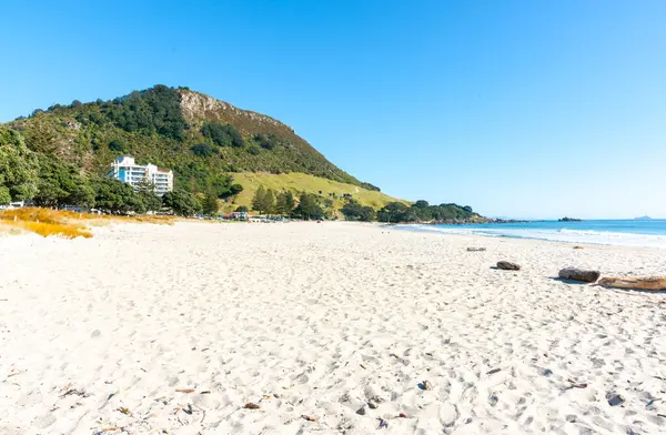 Maunganui Dağı, mavi gökyüzünün altında, uzun kumlu plajın sonunda Yeni Zelanda 'da..