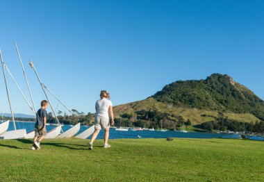 Maunganui Dağı Yeni Zelanda - 9 Nisan 2012; Anne ve oğlu çimen kenarında yürür Maunganui Dağı 'na.