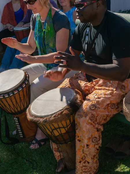 Tauranga Yeni Zelanda - 9 Nisan 2012; Tauranga Tarih Köyü 'nde siyahi erkek ve beyaz kadın birlikte Afrika davulu çalıyorlar.