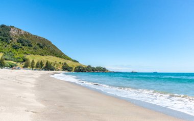 Long Sandy Main Sahili, Maunganui Dağı 'nın yeşil simgesine çıkıyor.