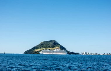 Tauranga Yeni Zelanda - 6 Mart 2024; Ufukta Maunganui Dağı simgesiyle Tauranga Limanı 'na giren ve çıkan büyük yolcu gemisi.