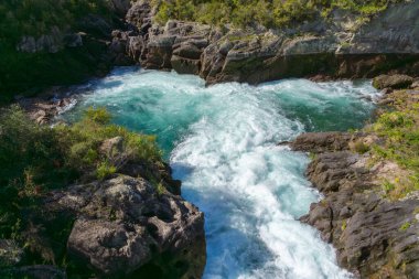 Su, Aratiatia, Taupo 'daki kayalık çıkıntılar arasında turkuaz yeşil havuza taşar..