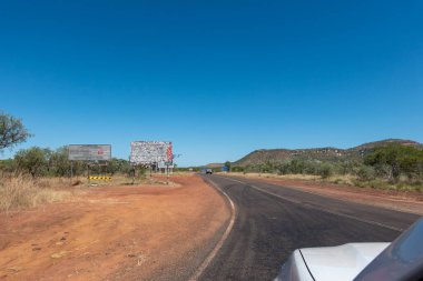 Batı Avustralya - 11 Mayıs 2025; Gibb Nehri Yolu 'na uzanan kırsal ve uzak arazide Büyük Kuzey Otoyolu' nu geçmek ve çıkartmalarla kaplı ikonik büyük levhaları geçmek.