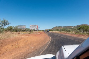 Batı Avustralya - 11 Mayıs 2025; Gibb Nehri Yolu 'na uzanan kırsal ve uzak arazide Büyük Kuzey Otoyolu' nu geçmek ve çıkartmalarla kaplı ikonik büyük levhaları geçmek.