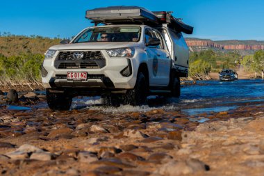 El Questro Avustralya - 11 Mayıs 2025; Kimberley Batı Avustralya 'da Pentekost Nehri' nin kıyısından geçen ve mavi gökyüzünün altında akan bir araç.