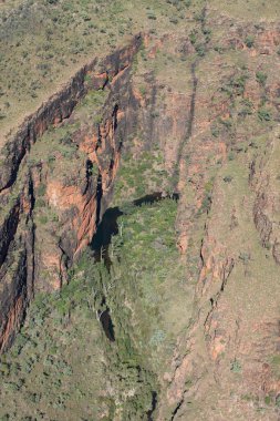 Kimberley Bölgesi 'nin dik kırmızı kayalık yüzleri güneş tarafından aydınlatılıyor. Batı Avustralya' nın üzerinde ay yükseliyor..