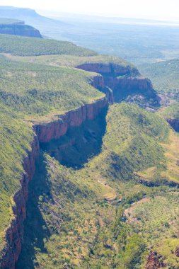 Kimberley Bölgesi 'nin dik kırmızı kayalık yüzleri güneş tarafından aydınlatılıyor. Batı Avustralya' nın üzerinde ay yükseliyor..