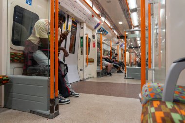 Londra İngiltere - 3 Temmuz 2025; Londra yeraltı tren vagonundaki gezginler cep telefonlarını kontrol etmek için zaman kullanıyorlar.