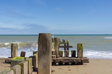 Ufuk çizgisini geçtikten sonra deniz yosunları ve midye kaplı sahil koruma damızlıkları Norfolk 'taki Walcott' ta tipik bir İngiliz plajında denize açılıyor..