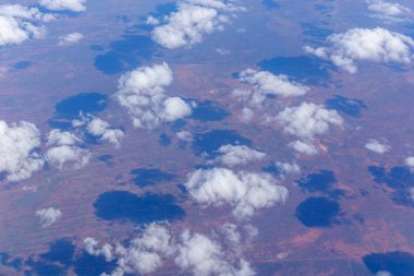 Beyaz kabarık bulutlar Avustralya 'nın kırmızı merkezi üzerine gölge düşürüyor..