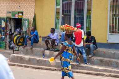 Kigali Rwanda - 3 Eylül 2025; Kafasında bir tepsi domates olan kadın şehir sahnesinde Afrika şehir caddesinde yürüyor.