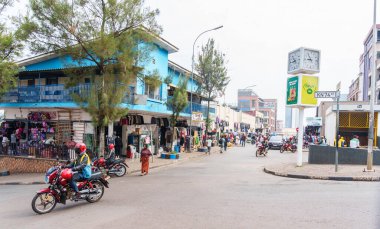 Kigali Rwanda - 4 Eylül 2025; Perakende ve binalarla sokak kavşağı ve motosiklet geçerken büyük saat.