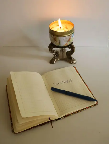 Defterin yanındaki metal bir şamdanda mum yakıyor.