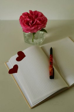 Kırmızı güller, defter, kalem ve kalpler. Sevgililer Günü geçmişi.