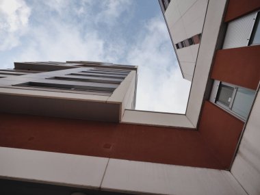 Kırmızı duvarlar, dikdörtgen pencereler ve beyaz ve gri panelleri olan bir yapıya sahip modern binaların alçak açılı görüntüsü. Mimari çağdaş, keskin çizgileri vurguluyor. 