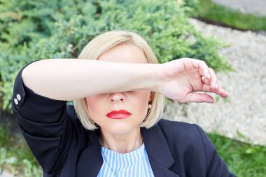 Bir kadın, iş saatinde yorgunluktan elini yüzünü kapatır.