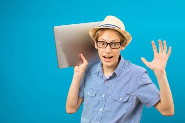Waist up portrait view of the funny businessman teen holding laptop in hands. Indoor studio shot isolated on blue background