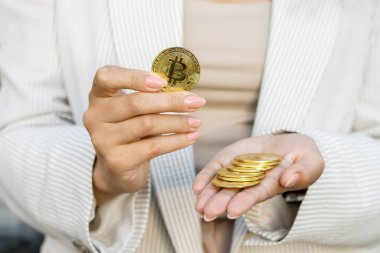 El ele tutuşan altın bitcoin, reklam parası, kripto para, dijital para, elektronik yatırım için kopya alanı. Bitcoin tutan iş kadınının kesilmiş portresi ve bunu kameraya gösteriyor. Satış ve iş konsepti