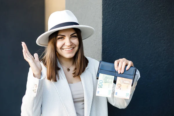 A picture of a happy pretty woman with a wallet with euro banknotes