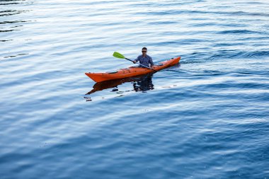 Nehirde kano yapıyorum. Genç beyaz bir adam kano ve kürek içinde oturur. Su eğlencesi konsepti.