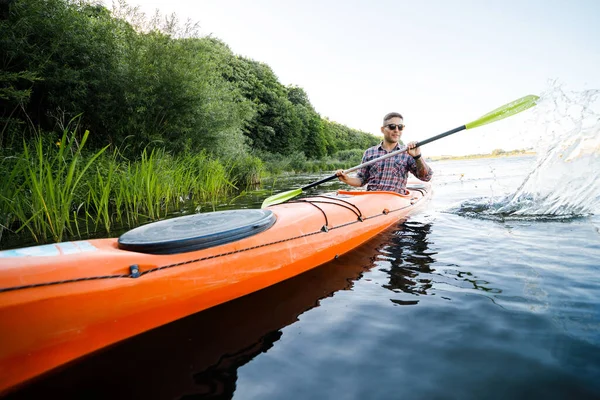 Kayaking on the river. A young Caucasian man sits in a kayak and paddles. The concept of water entertainment.