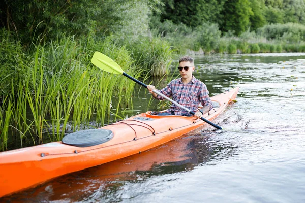 Kayaking on the river. A young Caucasian man sits in a kayak and paddles. The concept of water entertainment.