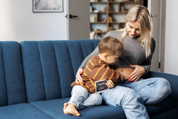 Young Pregnant Woman Her Son Sit Sofa Home Boy Holds — Fotografia de Stock