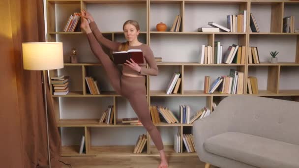 Jonge Vrouw Sportkleding Strekkende Benen Doet Splits Staand Bibliotheek Leesboek — Stockvideo