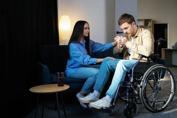 Young man in a wheelchair. Girlfriend comforting her sad boyfriend.