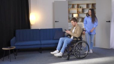 Genç ve güzel bir kız tekerlekli sandalyeye mahkum arkadaşına yardım ediyor.