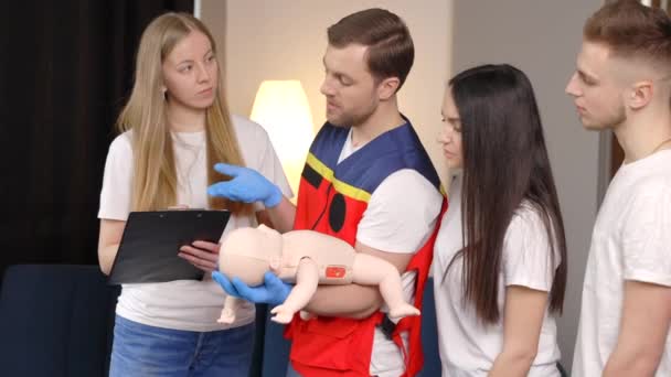 屋内での訓練中にダミーの子供と一緒に応急処置をする方法を学ぶ人々のグループ — ストック動画
