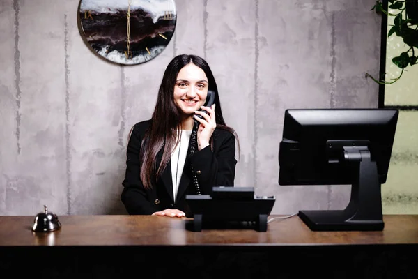 ホテル受付係 ベル付きのモダンなホテルのフロントデスク ホテルのカウンターに立って電話で話す幸せな女性受付係 — ストック写真