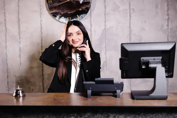 ホテル受付係 ベル付きのモダンなホテルのフロントデスク ホテルのカウンターに立って電話で話す幸せな女性受付係 — ストック写真