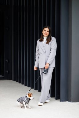 En sevdiği tüylü, eğitimli safkan Jack Russell Terrier köpeğiyle, sonbahar günü açık havada duvarın yanında köpek kostümü giymiş bir kadın. Sadık en iyi arkadaşlar