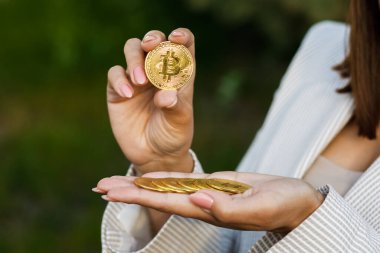 El ele tutuşan altın bitcoin, reklam parası, kripto para, dijital para, elektronik yatırım için kopya alanı. Bitcoin tutan iş kadınının kesilmiş portresi ve bunu kameraya gösteriyor. Satış ve iş konsepti