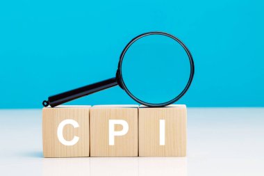 CPI - Tüketici Fiyat Endeksi sembolü. Harf bloğu kelime CPI kısaltması ile mavi arka plan üzerinde büyüteç ile. Kopya alanı. İş ve CPI, tüketici fiyat endeksi kavramı