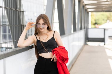 Stylish adorable pretty woman with long hair wearing black stylish suit and sunglasses standing and having fun in the street.