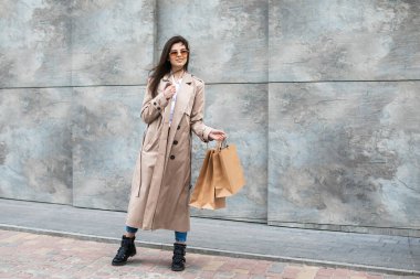 Alışveriş merkezinin yakınındaki alışveriş poşetleriyle sıradan kıyafetler içinde bir kız size paketini, tüketim satışını ve insanların konseptini sunuyor..